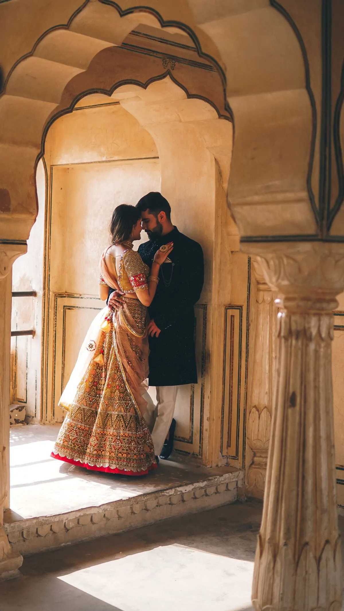 A couple in traditional Indian attire, smiling at each other